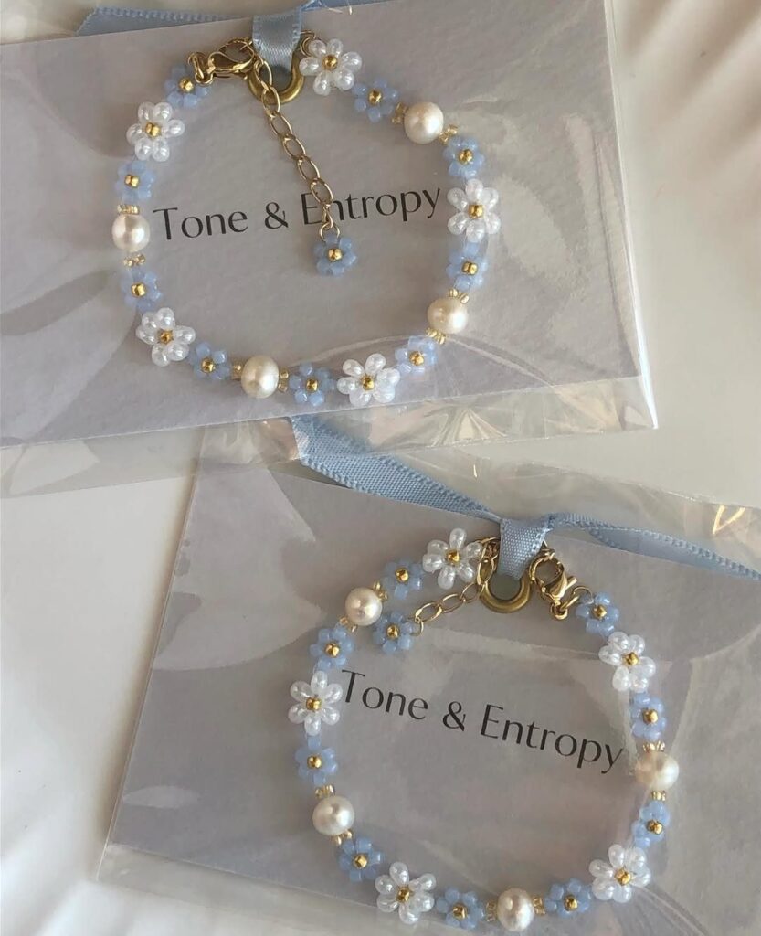Two blue and white beaded bracelets with flower clusters in clear packaging.