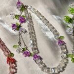 Beaded necklaces with clear and pink crystals and small purple flower accents.