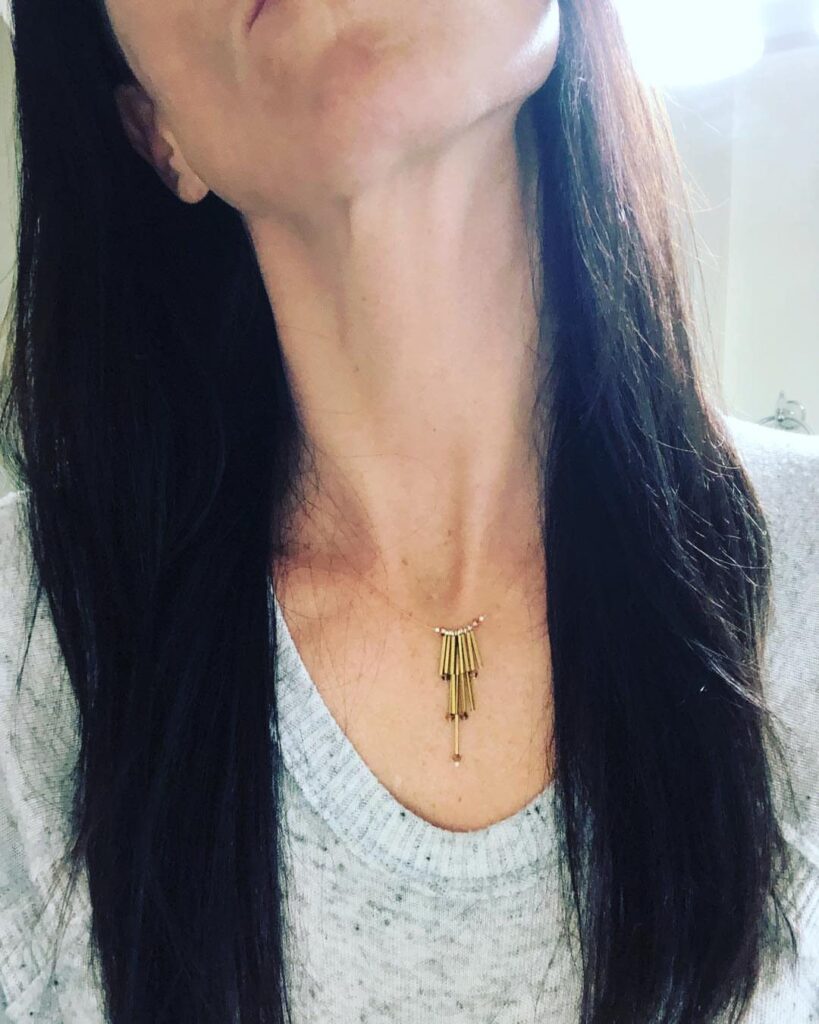 Copper tube necklace with vertical bars worn by a person with dark hair