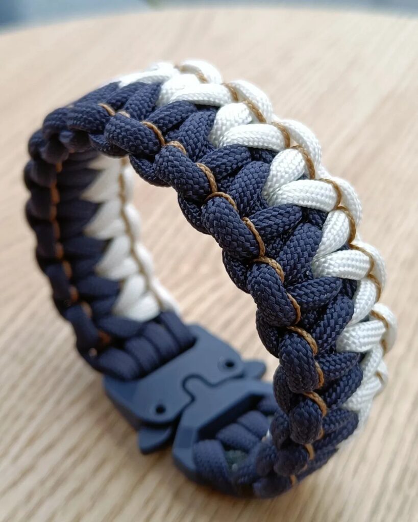 Woven navy blue and white paracord survival bracelet with a black plastic buckle.