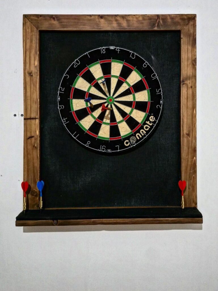 Dartboard mounted on a black backboard with a wooden frame and ledge.