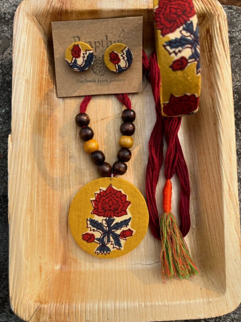 Fabric jewellery set with red floral embroidery on yellow fabric in wooden tray